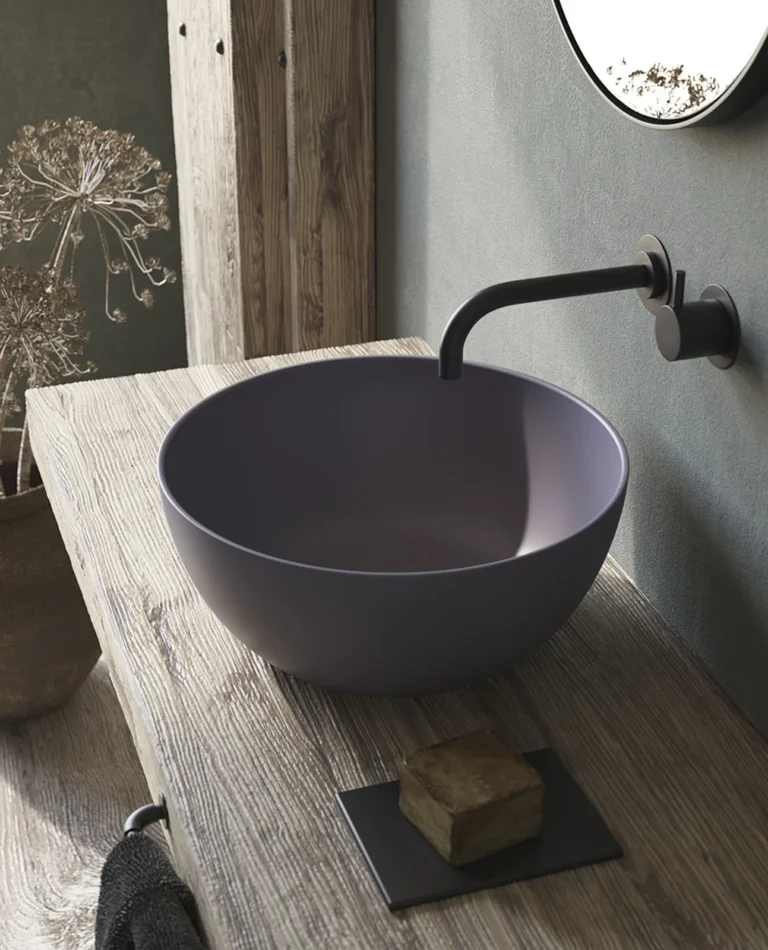 Violettes rundes Dream-Aufsatzwaschbecken vor einer grauen Wand auf einer Holzkonsole