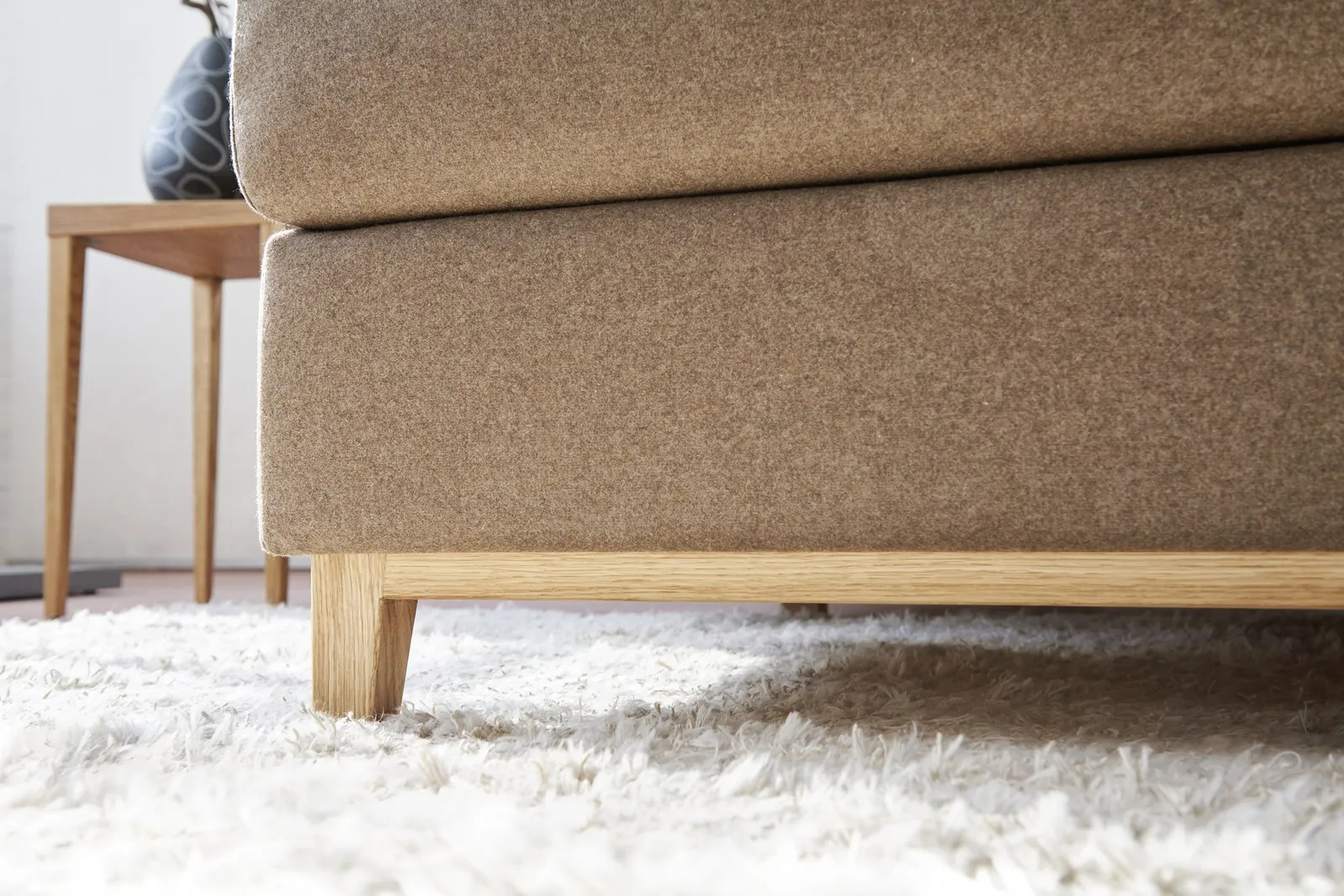 Beigefarbener Bezug und helles Holzgestell des Good-Life-Sofas im Detail.