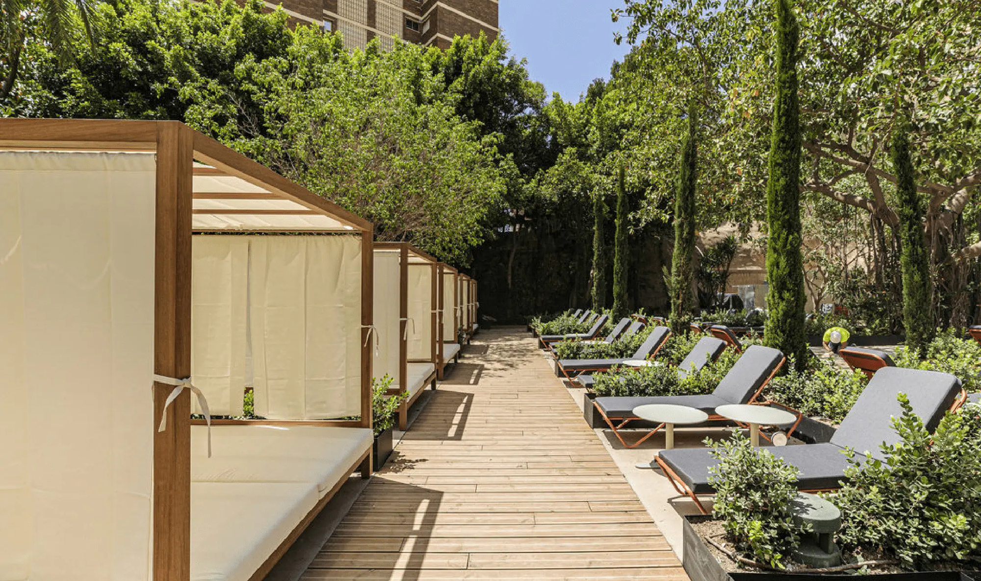 Barceloneta-Liegen mit grauen Auflagen entlang eines Holzstegs neben Cabanas