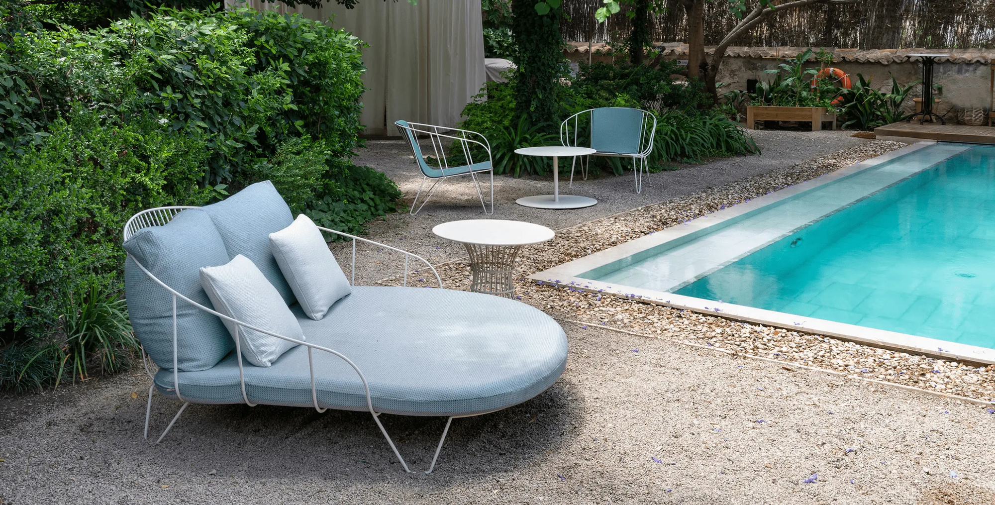 Hellblau gepolstertes Olivo Daybed mit weißem Gestell am Pool