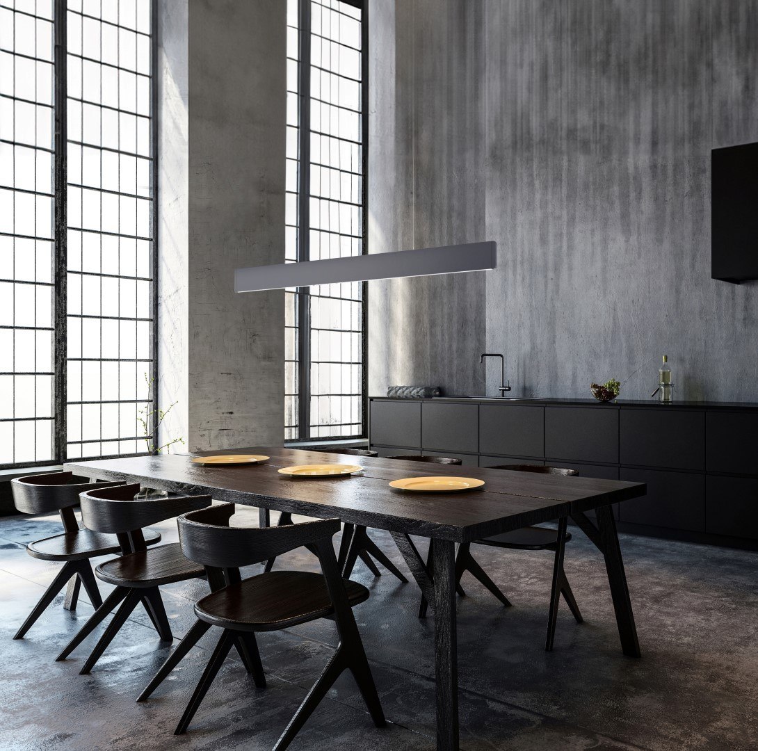 Molto Luce After8 Long: lange Pendelleuchte über einem dunklen Esstisch vor hohen Fenstern und einer Betonwand
