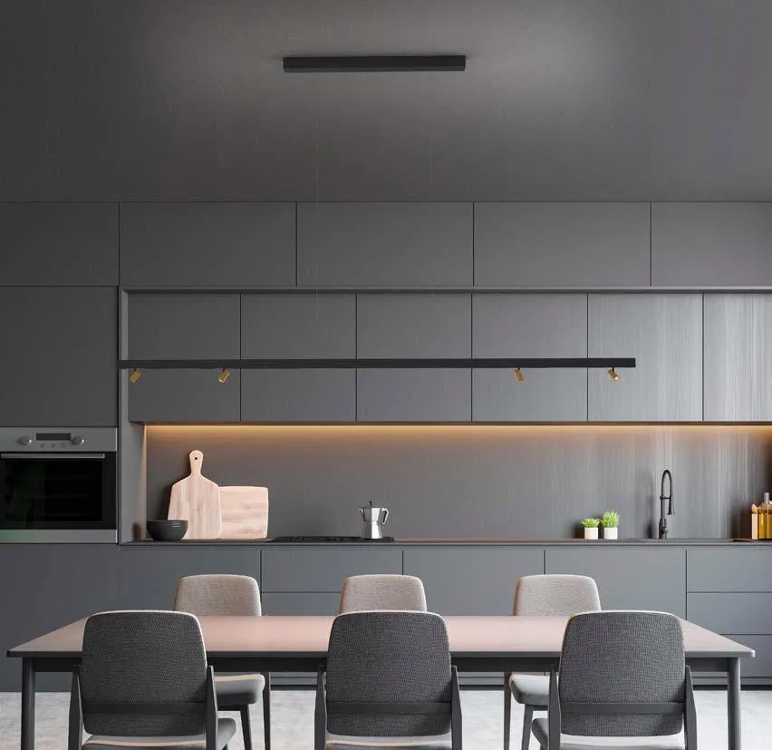 Molto Luce Magnetics: abgependeltes schwarzes Profil mit goldfarbenen Strahlern über einem Esstisch vor einer grauen Küche