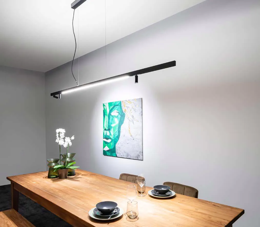 Molto Luce Magnetics: abgependeltes Profil mit Lichtlinie und Strahlern über einem gedeckten Holzesstisch