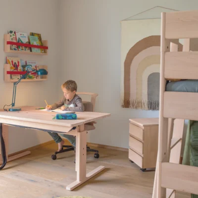 TEAM 7 kids Schreibtisch aus hellem Holz mit Drehstuhl und Rollcontainer im eingerichteten Kinderzimmer