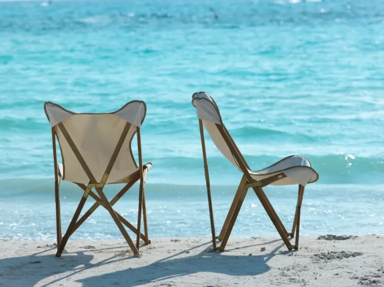 Zwei Unopiù Emy Klappsessel mit hellen Sitzbezügen am Strand, von hinten und seitlich
