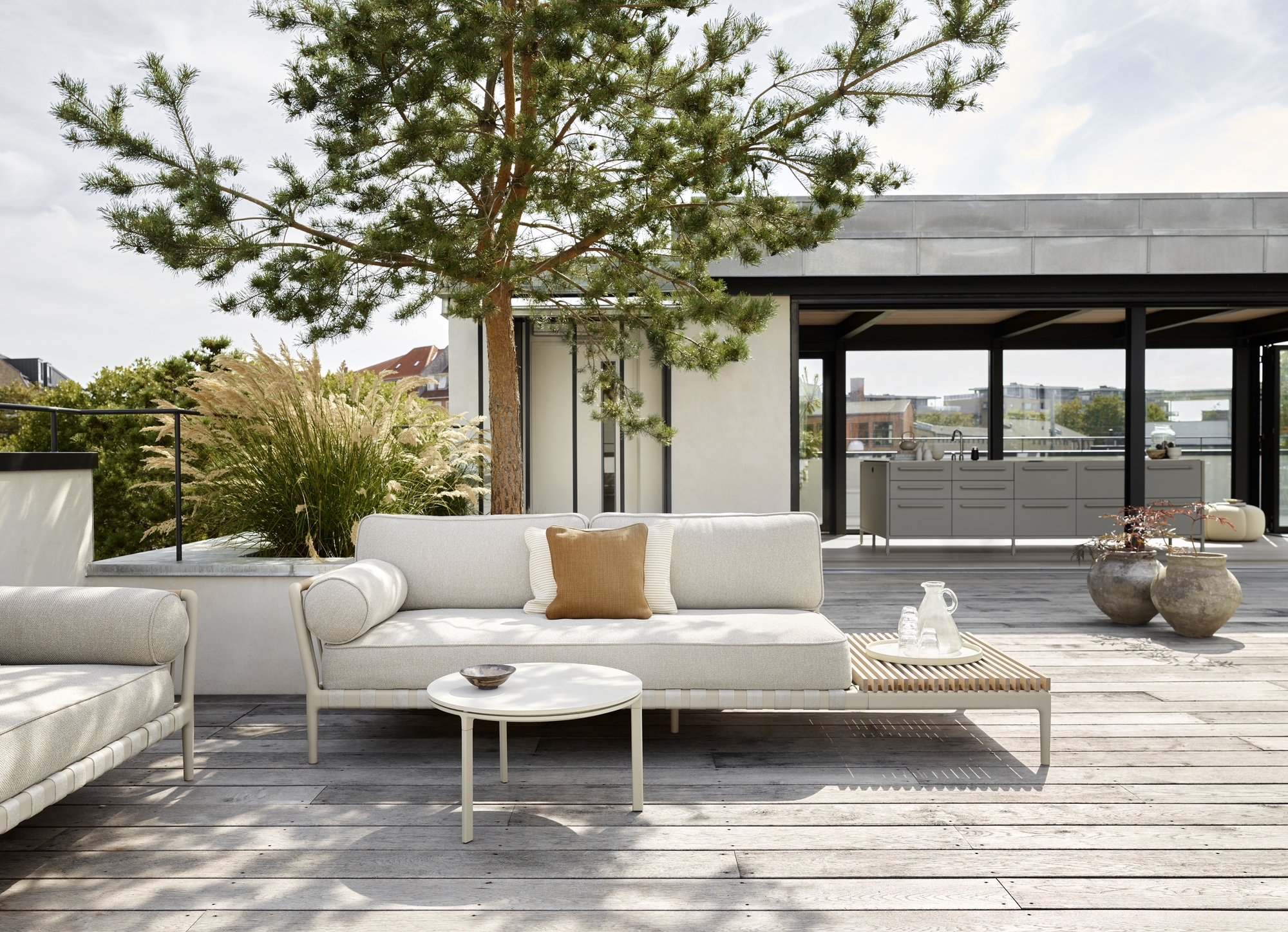 Helles Vipp 720 Outdoor-Sofa mit Holz-Beistelltisch auf einer Terrasse im Grünen